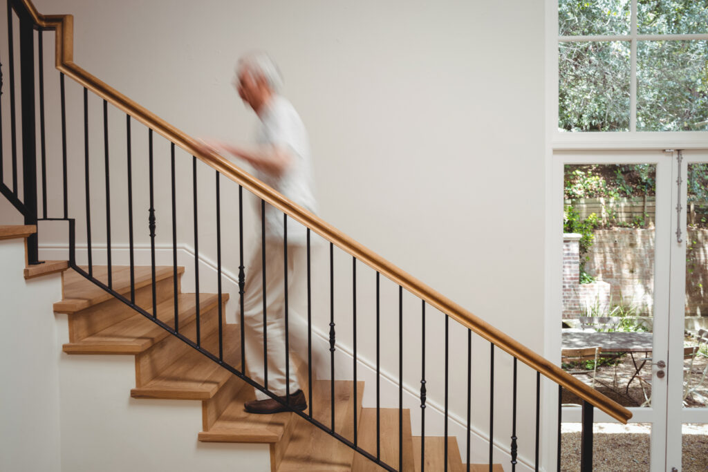 Senior man walking up stairs holding at home